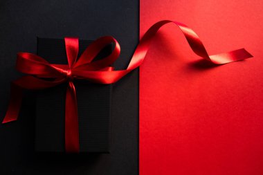 Siyah ve kırmızı arka planda siyah hediye kutusu. Tutkuyla sunar. Sevgililer Günü. Mutlu ilişkiler.  