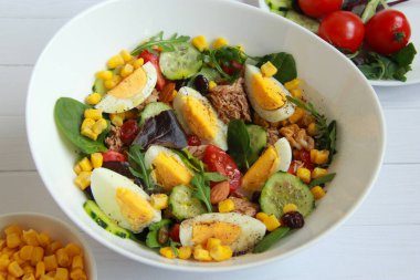 Mısır, yumurta, karışık salata, vişneli domates ve salatalıklı ev yapımı ton balığı salatası sağlıklı bir akşam yemeği.