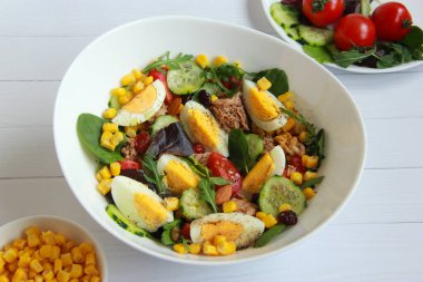 Mısır, yumurta, karışık salata, vişneli domates ve salatalıklı ev yapımı ton balığı salatası sağlıklı bir akşam yemeği.