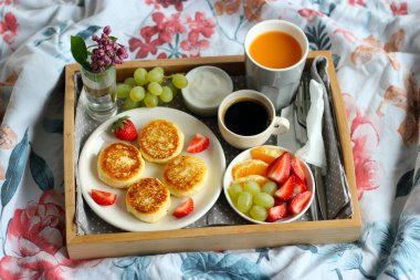 Breakfast in bed - cottage cheese cheesecakes with black coffee, orange juice, sour cream and fresh fruits clipart