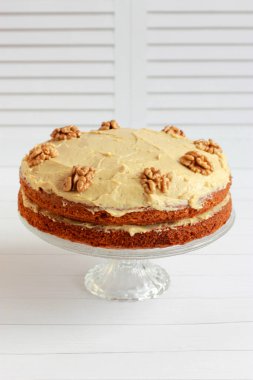 Ceviz yarısıyla süslenmiş kremalı cevizli ve kahveli kek. Tereyağlı ve kremalı ev yapımı vejetaryen pastası.