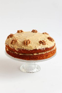 Ceviz yarısıyla süslenmiş kremalı cevizli ve kahveli kek. Tereyağlı ve kremalı ev yapımı vejetaryen pastası.