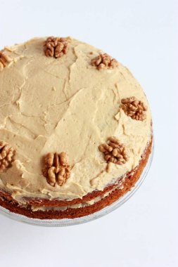 Ceviz yarısıyla süslenmiş kremalı cevizli ve kahveli kek. Tereyağlı ve kremalı ev yapımı vejetaryen pastası.