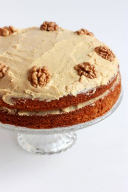 Ceviz yarısıyla süslenmiş kremalı cevizli ve kahveli kek. Tereyağlı ve kremalı ev yapımı vejetaryen pastası.