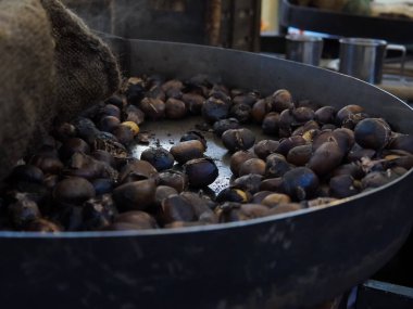 Big hot pan of roasted chestnuts with smoke ,italian street food. High quality photo
