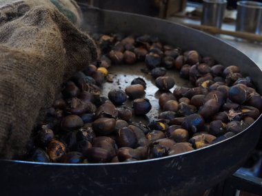 Big hot pan of roasted chestnuts with smoke ,italian street food. High quality photo