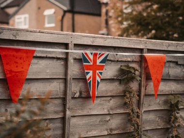 Büyük Britanya bayrakları İngiliz evinin bahçesinde rüzgarda sallanıyor, taç giyme töreni kutlaması. .