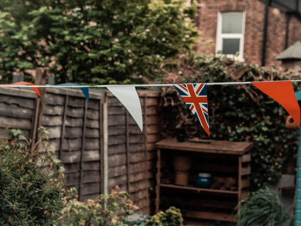 stock image Flags of Great Britain waving on the wind in the garden of English house,coronation celebration .