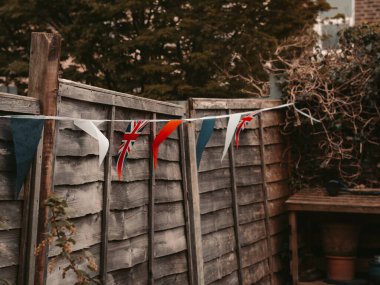 Büyük Britanya bayrakları İngiliz evinin bahçesinde rüzgarda sallanıyor, taç giyme töreni kutlaması. .