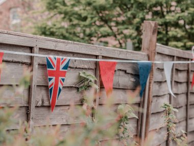 Büyük Britanya bayrakları İngiliz evinin bahçesinde rüzgarda sallanıyor, taç giyme töreni kutlaması. .