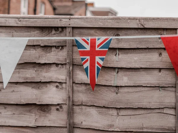 stock image Flags of Great Britain waving on the wind in the garden of English house,coronation celebration .