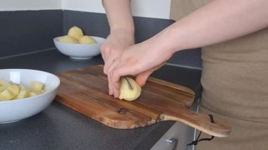 Kadının elleri mutfakta çiğ patates soyuyor, akşam yemeği pişiriyor. 
