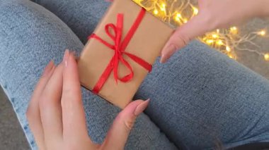 Kadınların elinde kırmızı kurdele olan küçük bir Noel hediyesi. Yüksek kalite 4k görüntü