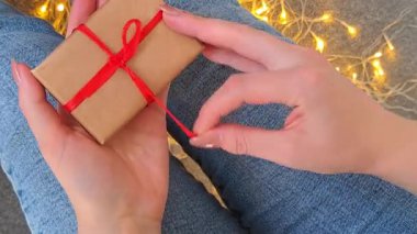 Kadınların elinde kırmızı kurdele olan küçük bir Noel hediyesi. Yüksek kalite 4k görüntü