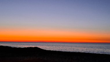 Güneş ufkun altına batıyor. Huzurlu denizde sıcak altın bir parıltı yayıyor.