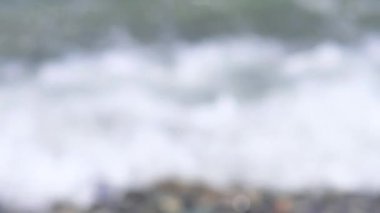 Bulanık deniz dalgalarının sakin sahnesi çakıl taşlı bir kıyıya yavaşça vuruyor.