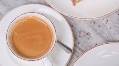 Kafe masasında beyaz bir fincanda kremalı kahve. Huzurlu bir kahvaltı için mükemmel....