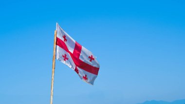 Georgia bayrağı mavi gökyüzüne yakın, rüzgarda gururla sallanıyor