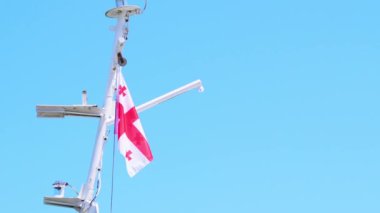 Georgia bayrağı mavi gökyüzüne yakın, rüzgarda gururla sallanıyor.