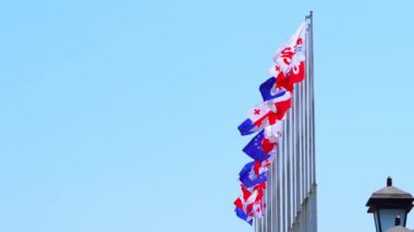 Georgia bayrağı mavi gökyüzüne yakın, rüzgarda gururla sallanıyor.