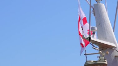 Georgia bayrağı mavi gökyüzüne yakın, rüzgarda gururla sallanıyor.