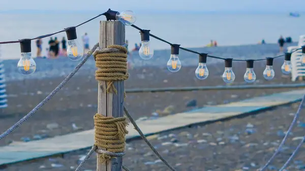 stock image close up of garland lights in cafe in the summer evening on the beach.