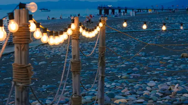 stock image close up of garland lights in cafe in the summer evening on the beach.