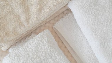 Beyaz ve bej havlular düzgünce istiflenmiş, zarafet ve rahatlık katıyor.