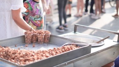 Arka planda bulanık insanlar olan bir sokak yemekçisine yakın plan karamelli fındık....