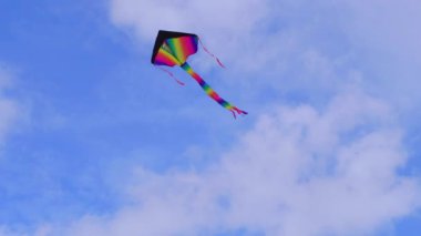Mavi gökyüzünde uçan canlı bir uçurtma, yaz etkinlikleri ve eğitici kullanım için mükemmel. Yüksek kalite 4k görüntü