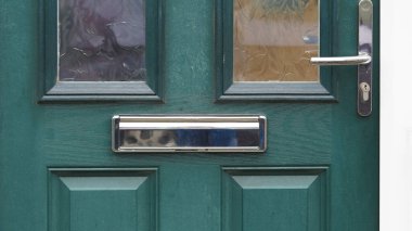 İngiliz kırmızı kapısı, pirinç tokmağı ve uyumlu posta kutusu, sokak manzaralı.