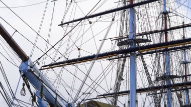 Atışlar, halatlar, gemi direğinde askılar, mavi gökyüzü ve deniz arka planı, yelken.