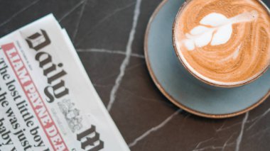 Sabah gazetesinin yanında karışık desenli bir lattenin yakın çekimi..