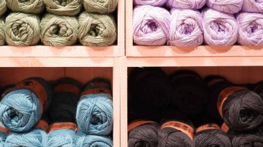 Bir mağaza vitrininde sergilenen renkli iplikler yaratıcılığı ve sıcaklığı davet ediyor..