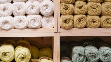 Bir mağaza vitrininde sergilenen renkli iplikler yaratıcılığı ve sıcaklığı davet ediyor..