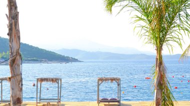 Turkuaz suyu ve altın kumu olan yaz plajı, parlak güneş ışığı altında tatil konsepti..