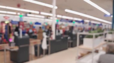 Marketin içi bulanık, alışveriş arabalarını iten insanlarla dolu..