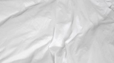 Beyaz çarşaflı, zarif yapılmamış yatak. Huzurlu ve davetkar bir yer yaratıyor.