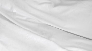 Beyaz çarşaflı, zarif yapılmamış yatak. Huzurlu ve davetkar bir yer yaratıyor.