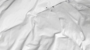 Yapılmamış beyaz bir yatak ve doğal sabah ışığı olan minimalist bir iç mekan.