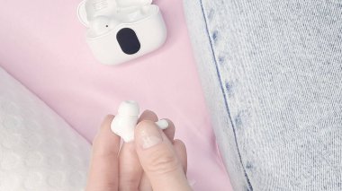  Parmakların, akıllı bir kulaklığı, tarafsız bir arkaplana nazikçe dayamış.