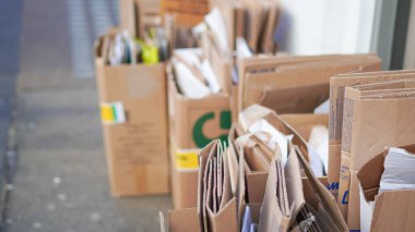 Recycled cardboard piles neatly stacked outside for waste management clipart