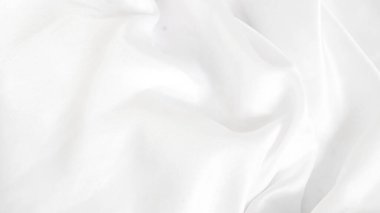 Yumuşak ışığı yansıtan parlak beyaz ipek kumaş, zengin bir doku yaratır.