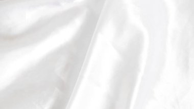 Yumuşak kıvrımları ve hafif ışık yansımaları olan pürüzsüz beyaz ipek kumaş