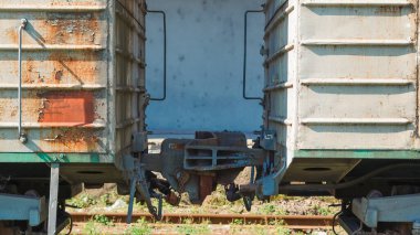 Endüstriyel tren vagonları paslı bir tren istasyonunda naklediliyor.