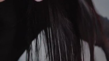 Uzun esmer saçlar, kuaförde saç kurutma makinesiyle kurutuluyor.