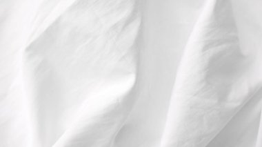 Yumuşak dokusu ve doğal ışıklandırması olan buruşuk beyaz yatak örtüsü