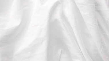 Doğal ışık ve rahat atmosferi olan kırışık beyaz çarşaf.