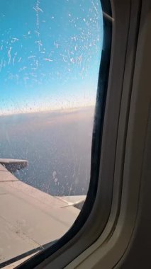 Uçuş sırasında bulutlu ve mavi gökyüzü olan uçak penceresinden görüntüle