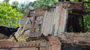 Ukrayna 'da yanan duvarları ve çökmüş çatısı olan savaş hasarlı ev cephesi.